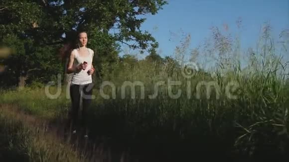 年轻的黑发女人在公园里跑步她在听音乐视频的预览图