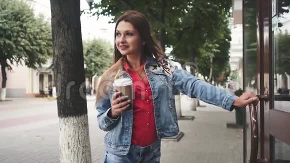 年轻女子站在咖啡厅前喝咖啡户外活动视频的预览图