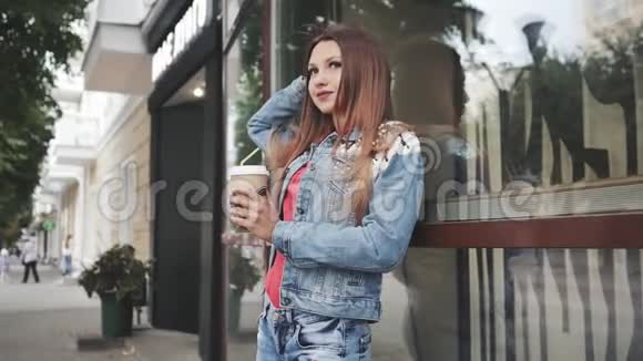 年轻的女人拿着咖啡站在镜子前户外活动视频的预览图