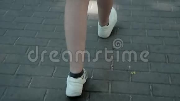 年轻漂亮的穿着白色运动鞋的女性脚在炎热的夏天走在瓷砖形状的菱形上视频的预览图
