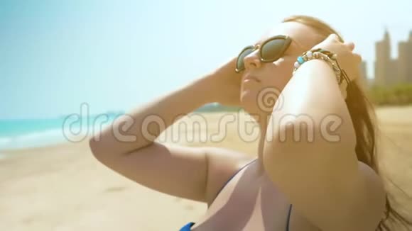 海滩上的年轻女孩调整她的头发近距离射击慢动作视频的预览图