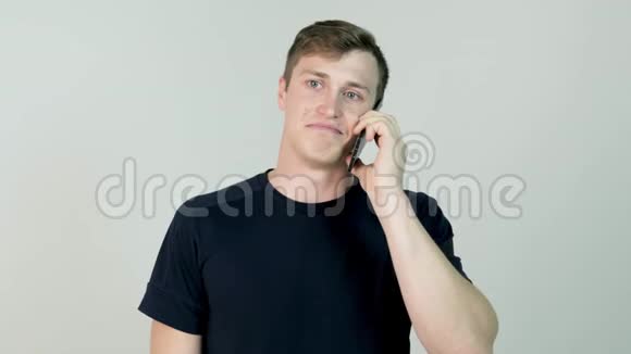 一个不经意的年轻人在电话里说话的肖像年轻人拿着手机站着和他说话视频的预览图