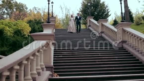 一个男人和一个穿着优雅衣服的女孩走下大楼梯沿着台阶走视频的预览图