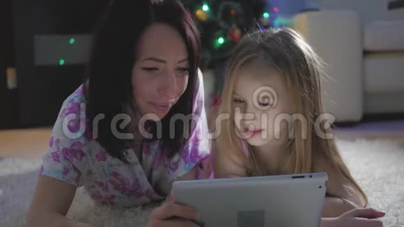 有趣的妈妈和可爱的女儿正在玩平板电脑充满爱意的家庭视频的预览图