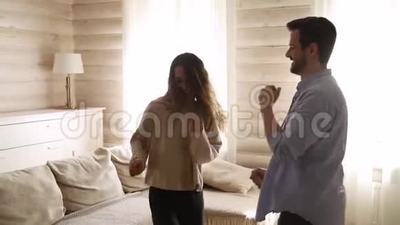 年轻无忧无虑的活跃情侣在家客厅里跳舞视频的预览图