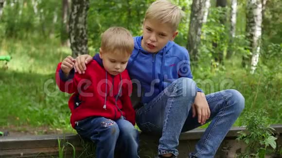 一个孤独的十几岁男孩和他的弟弟坐在火车轨道上视频的预览图