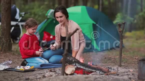 幸福的家庭在大自然中度过了美好的时光妈妈教女儿在明火上煮棉花糖视频的预览图