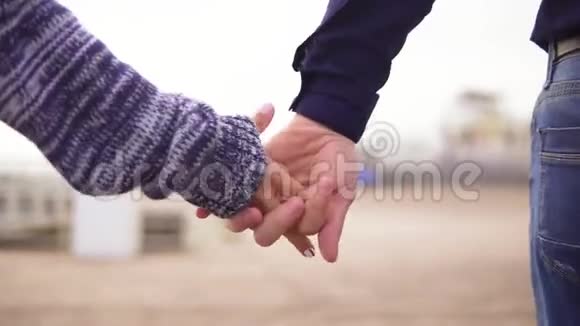 海滩上一对年轻夫妇牵着手一起散步的特写镜头慢镜头视频的预览图