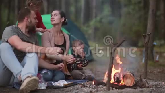 家人和他们的小儿子和女儿在大自然中休息他们在明火上煮棉花糖然后吃它们视频的预览图