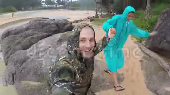 穿着雨衣在海滩上散步和微笑雨季泰国高清高精度视频的预览图