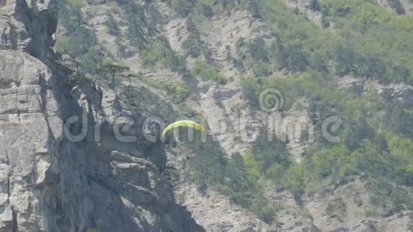 黄色滑翔伞在绿油油的克里米亚山脉背景下飞翔视频的预览图