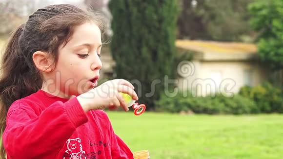 可爱的小女孩缓慢地吹着肥皂泡视频的预览图