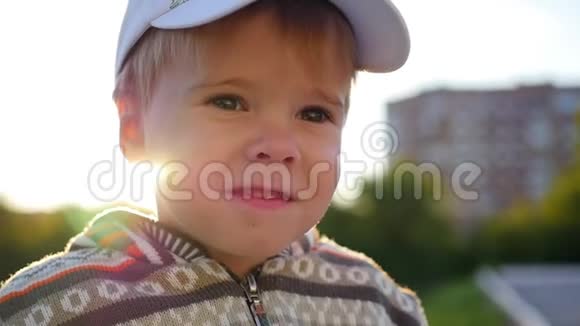 美丽的孩子看着相机在阳光的背景下微笑户外乐趣视频的预览图