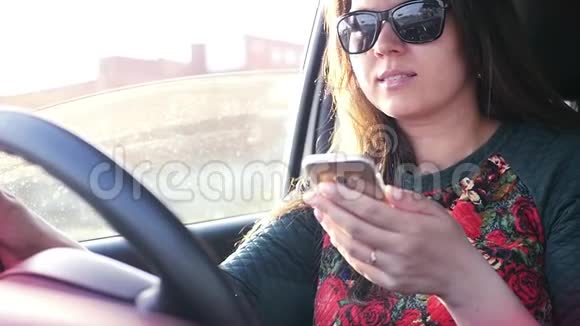 女孩开着车开着车是危险的手里拿着手机看着显示器慢动作视频的预览图