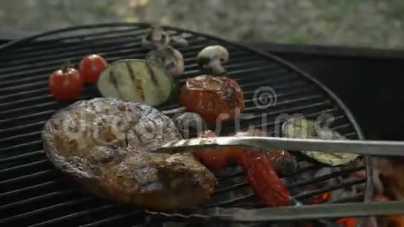 蔬菜和鱼烤架牛排鱼厨师在夏季餐厅露台的圆形烤架上用铁钳转动视频的预览图