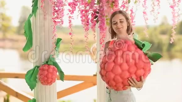 花艺女孩用一个大人造草莓装饰一个结婚拱门视频的预览图