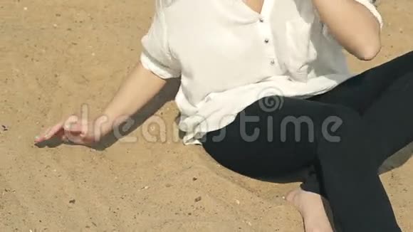 女孩坐在沙滩上把沙子倒进视频的预览图