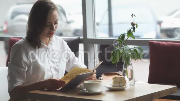女孩看书在咖啡馆放松穿商务服装的女孩在午休时休息视频的预览图