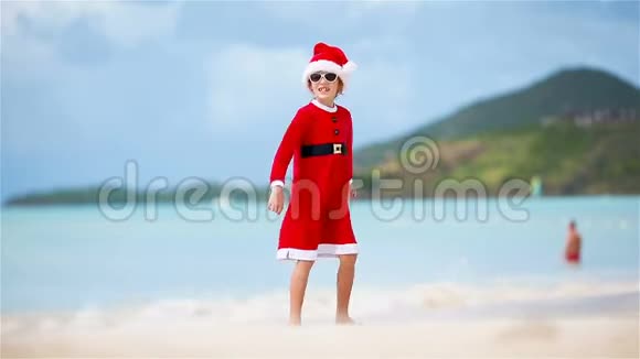圣诞节假期海滩上戴圣诞帽的可爱女孩的后景视频的预览图