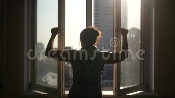一个年轻的女孩关上窗扇在房子和阳光的背景下转动钢笔慢动作视频的预览图