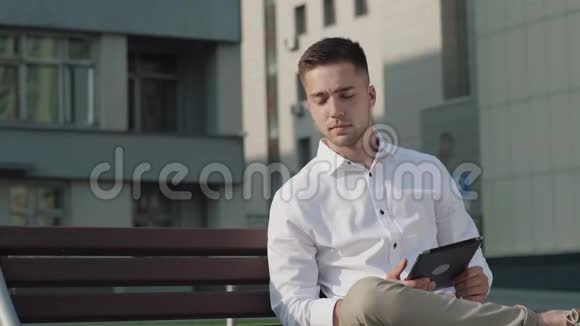 穿着白色休闲衬衫街上有平板电脑的年轻人视频的预览图