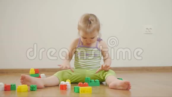 小女孩在彩色积木里玩耍坐在白色的背景上孩子和玩具视频的预览图