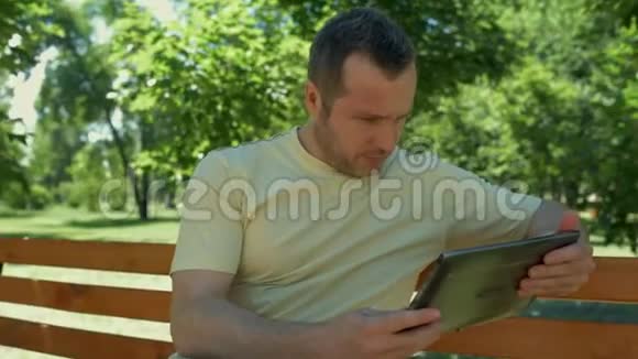 积极的人拿着笔记本电脑坐在公园里视频的预览图