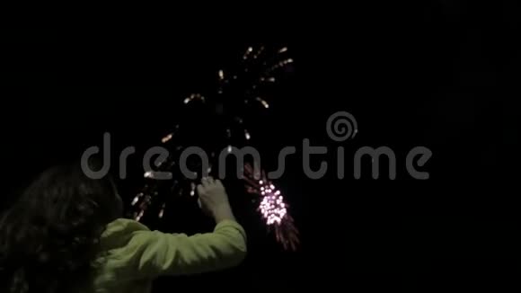 夜晚的女孩看着天空中的烟火美丽的烟花在夜间假日新年生日女孩视频的预览图