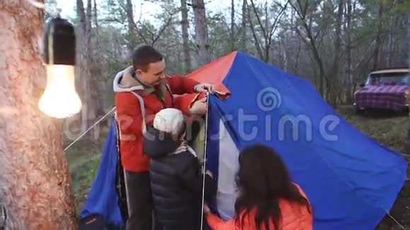 23年轻的一家人搭帐篷晚上在森林里在烧灯泡视频的预览图