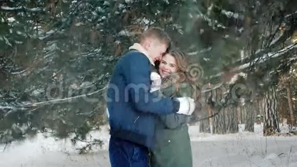 美丽的情侣在森林里相爱的冬天大雪纷飞的头上男生和女生都着快乐的年轻人视频的预览图
