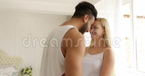 情侣相爱相拥微笑站着面对混血男人女人拥抱早间卧室视频的预览图