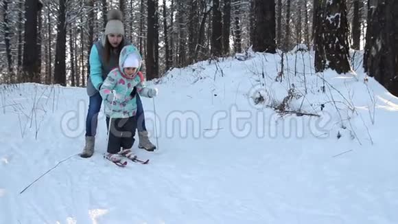 女孩正在学习滑雪她在松软的雪地里慢慢地滑上滑雪板冬天森林里美丽的一天妇女视频的预览图