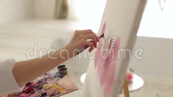 一个有创意的女孩在绘画工作室的白色画布上画花特写镜头视频的预览图