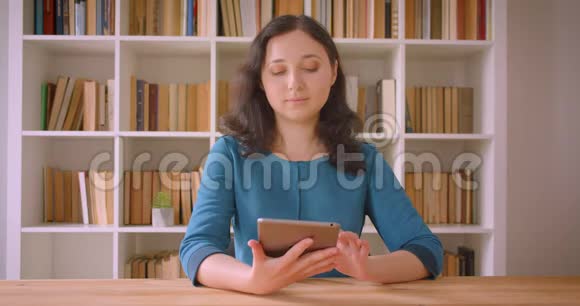 年轻漂亮的白种人女学生用平板电脑特写肖像并在镜头中显示绿色彩色屏幕视频的预览图