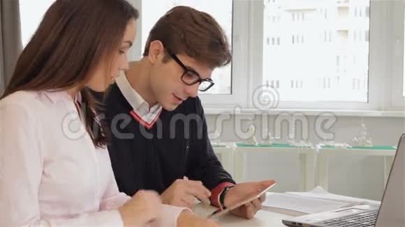 男人和女人在办公室里看着男人的平板电脑视频的预览图