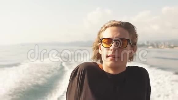 年轻的白种人时髦的家伙在游艇甲板上航行大海视频的预览图