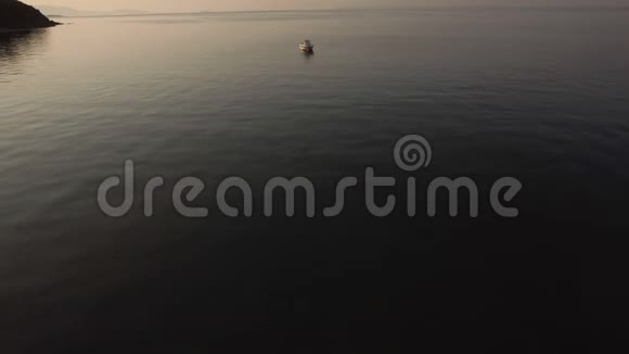 日落时在宁静的大海中空舟的鸟瞰视频的预览图