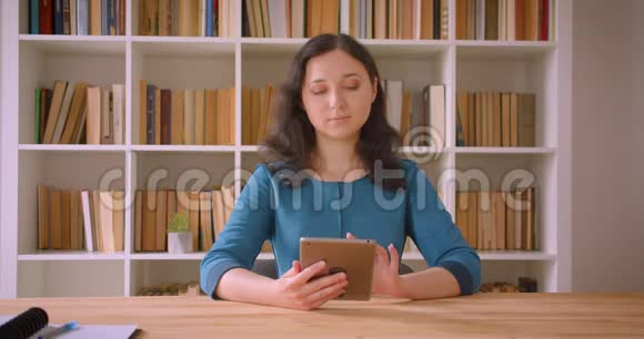 用平板电脑拍摄年轻漂亮的白种人女学生的特写肖像并在镜头中显示绿色屏幕视频的预览图