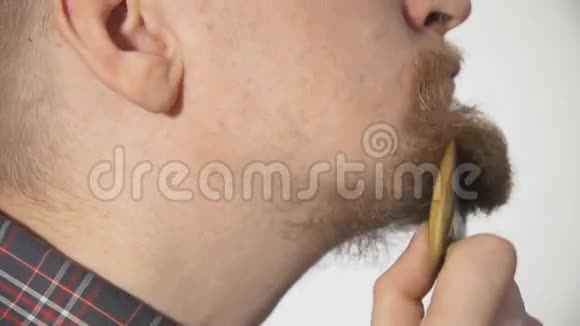 男人梳理白色背景上的胡须梳子拍摄特写视频的预览图