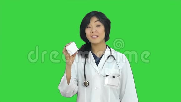 一位亚洲女医生在绿色屏幕上看着相机展示了一瓶药片ChromaKey视频的预览图