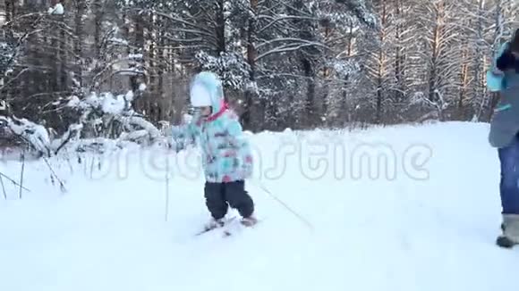 女孩正在学习滑雪她在松软的雪地里慢慢地滑上滑雪板冬天森林里美丽的一天妇女视频的预览图