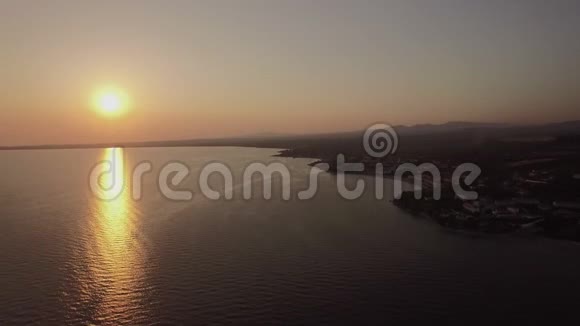 海上和沿海小镇日落时分空中希腊Trikorfo海滩远景视频的预览图