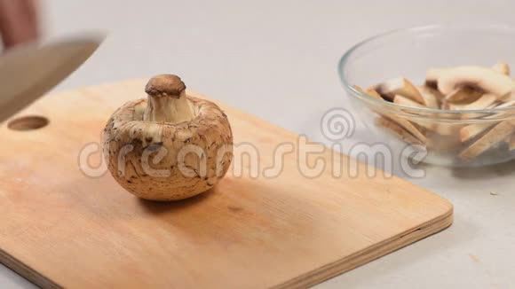 雄手用刀在切割板上切生蘑菇然后把它们折叠成玻璃碗视频的预览图