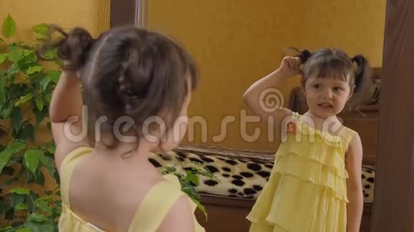 小女孩在镜子前扭尾巴一个头上有尾巴的漂亮女孩看着猫头鹰的倒影一杯视频的预览图