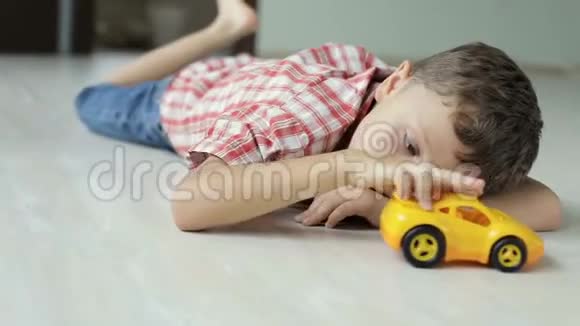 一个伤心的小男孩白天躺在家里的地板上视频的预览图