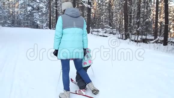 女孩正在学习滑雪她在松软的雪地里慢慢地滑上滑雪板冬天森林里美丽的一天妇女视频的预览图