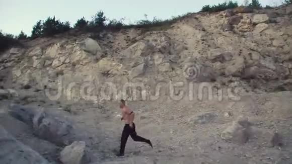 强壮的男人在粗糙的岩石上慢跑训练自由战斗4K视频的预览图