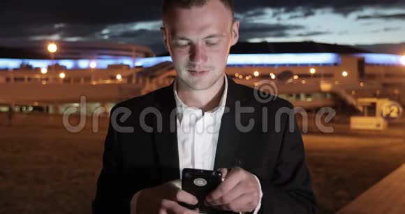 在城市的夜晚人们使用智能手机上的应用程序短信视频的预览图