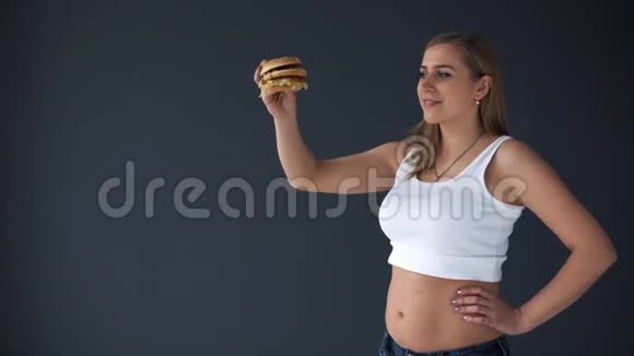超重的女人灰色背景上有汉堡包她想吃快餐视频的预览图