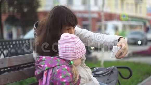 母亲和女儿坐在一条繁忙道路附近的长凳上带着sefi视频的预览图